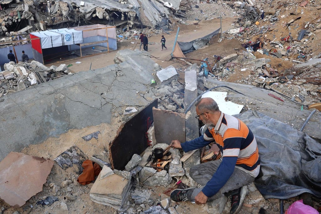 A man prepares coffee on the rubble of a building as displaced Palestinians return to the northern areas of the Gaza Strip, in Jabalia, on Thursday during the Israel-Hamas ceasefire. Photo: AFP