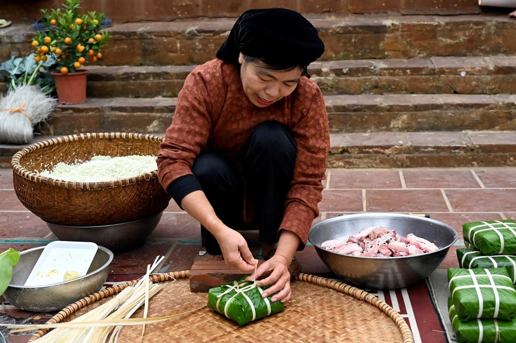 Nguyen Thi Thuy Hong wraps “banh chung” outside her house on the outskirts of Hanoi. Photo: AFP