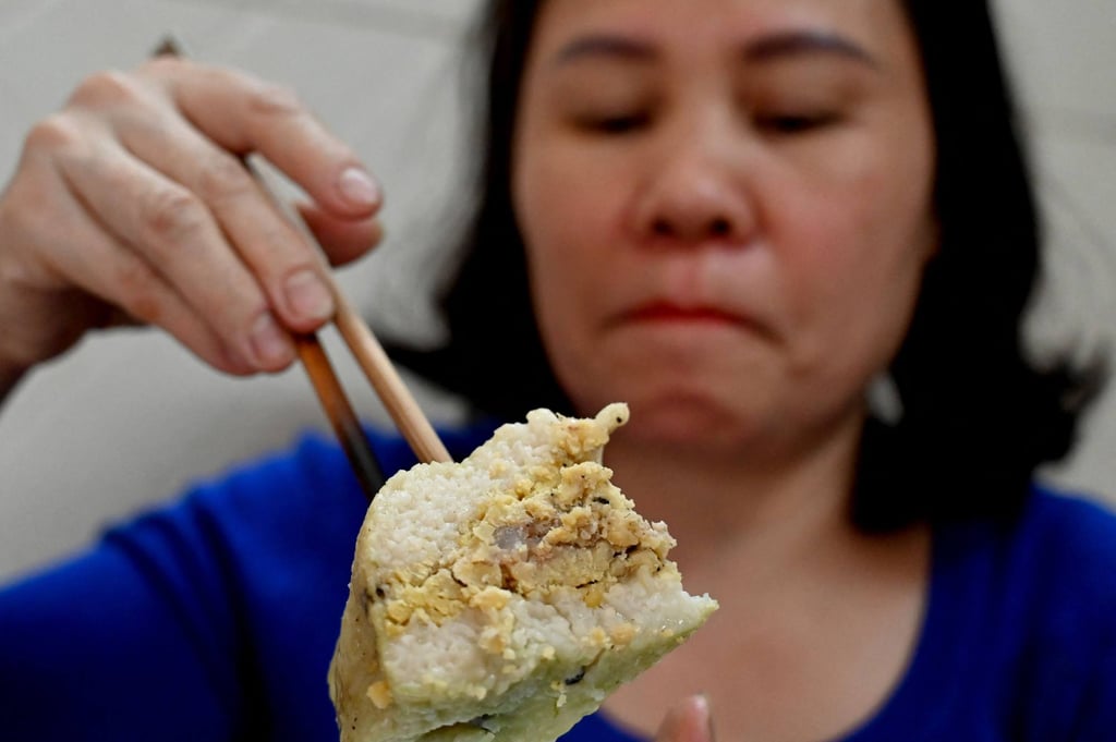 A Vietnamese woman eats “banh chung” rice cake in Hanoi. Photo: AFP