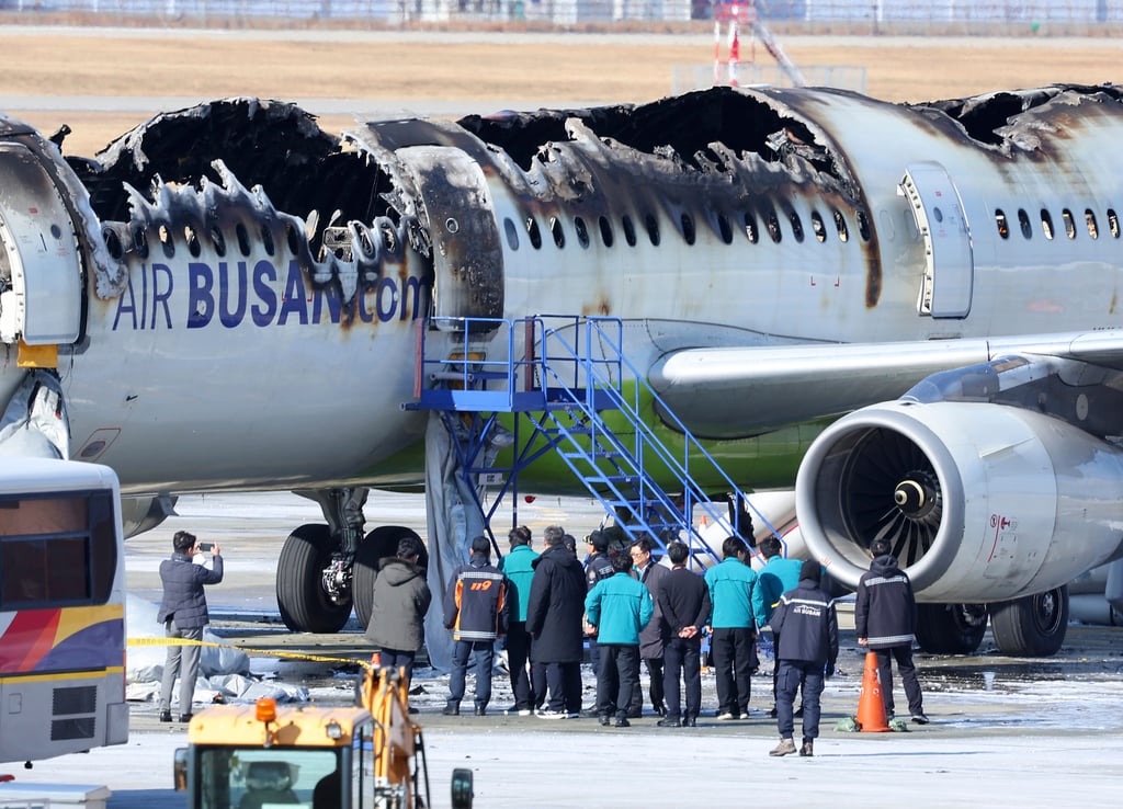 Firefighters and other officials inspect the remains of the Air Busan plane that caught fire at Gimhae International Airport, on Wednesday. Photo: Yonhap via AP