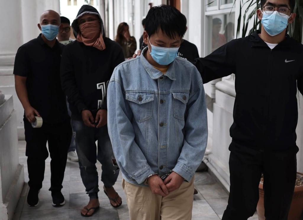Chinese national Deng Yuanqing (second from right) with an unidentified Filipino companion (second from left) are escorted inside the Department of Justice office in Manila, the Philippines, on January 20. Photo: EPA-EFE