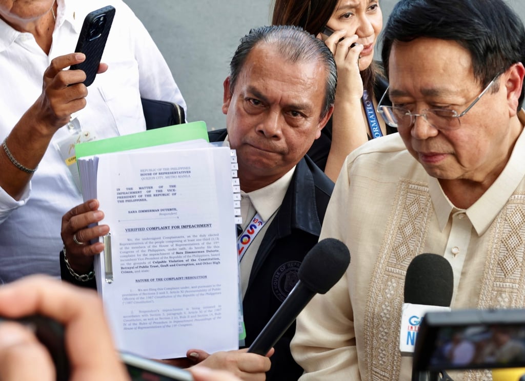 A staffer displays the Articles of Impeachment transmittal documents as House Secretary General Reginald Velasco (right) speaks to media on February 5. Photo: EPA-EFE