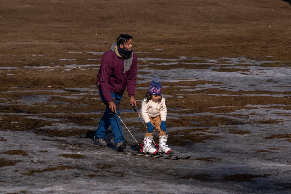 A ski instructor helps a young tourist practise skiing on a patch of melted snow in Gulmarg last winter. Photo: AP