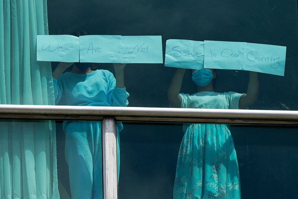 Women hold up signs pleading for help. Photo: AFP