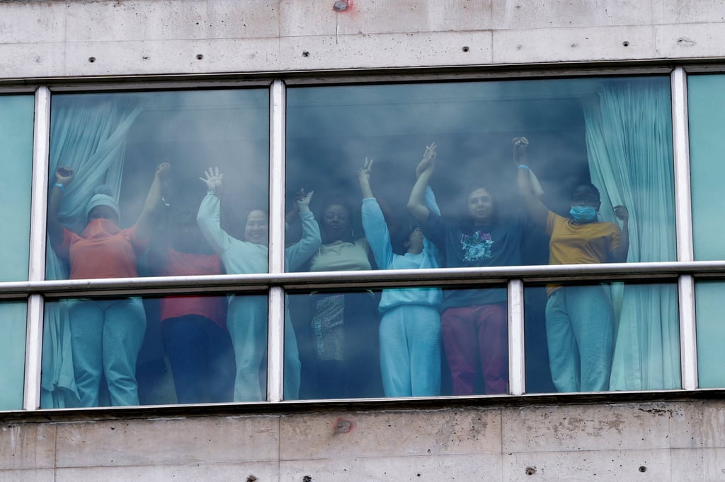 People hold hands at the window of the hotel. Photo: Reuters
