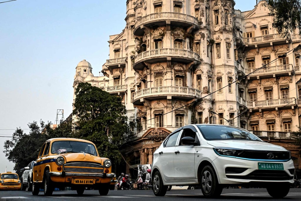A Tata Motors electric vehicle (right) riding past the Esplanade Mansion, a heritage building in Kolkata, India. Photo: Reuters