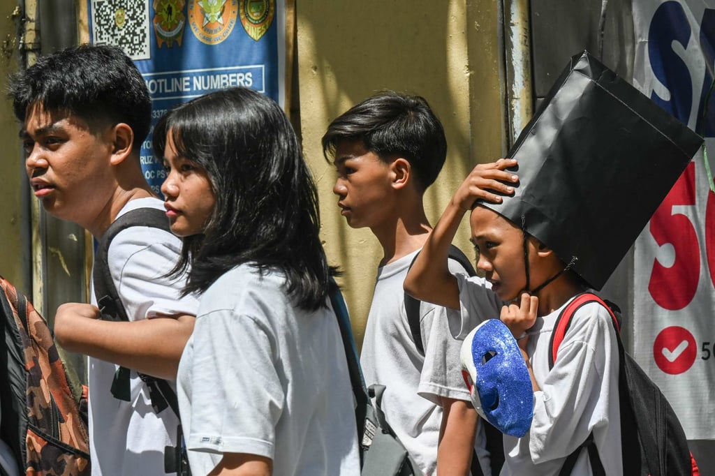 A student uses a paper bag to protect himself from the sun as he leaves school in Manila on Monday. Photo: AFP