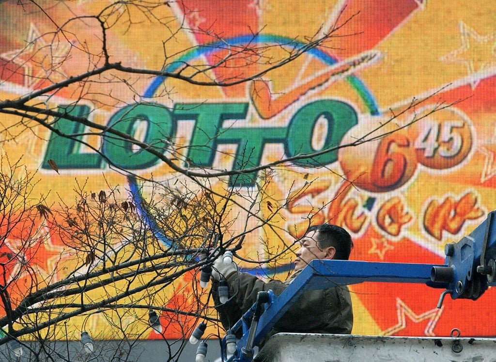 A worker removes street decorations in front of a screen advertising a lottery draw in Seoul. Photo: AFP