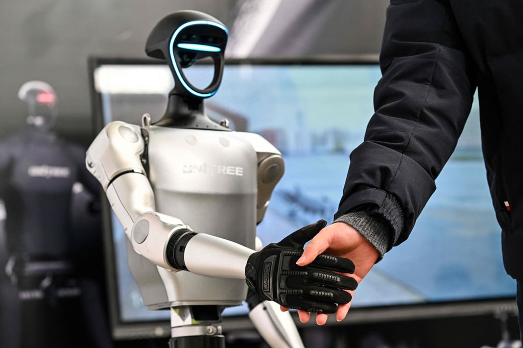 A man shakes hands with a humanoid robot from Unitree Robotics during the Global Developer Conference in Shanghai on February 21, 2025. Photo: AFP