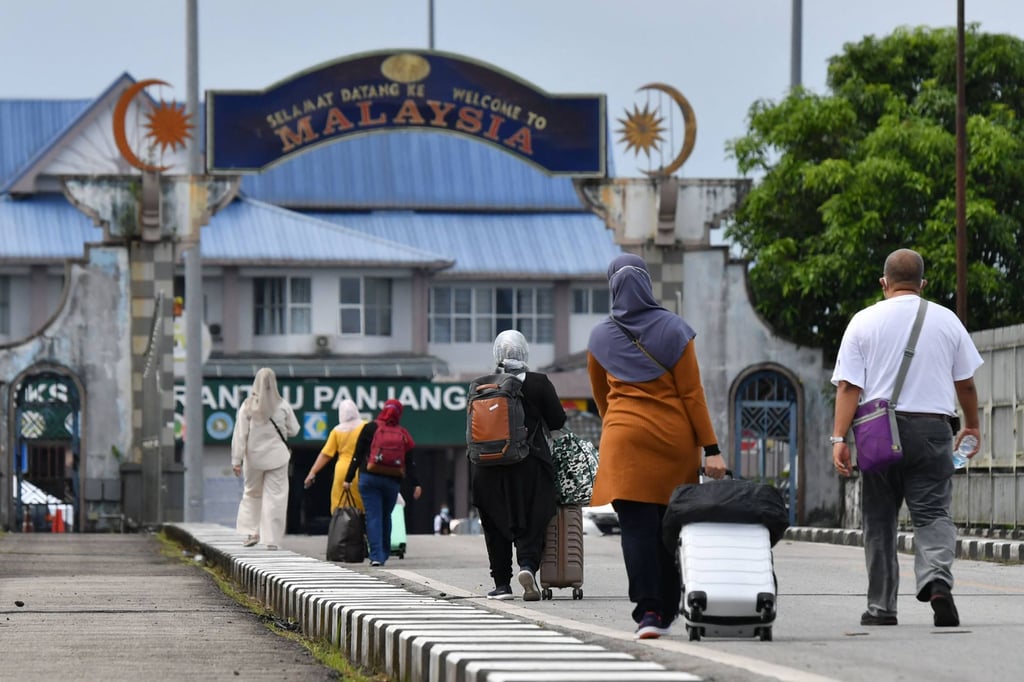 People walk with their luggage towards Malaysia at the border in Sungai Kolok district, southern Thailand’s Narathiwat province, in 2022. Photo: AFP
