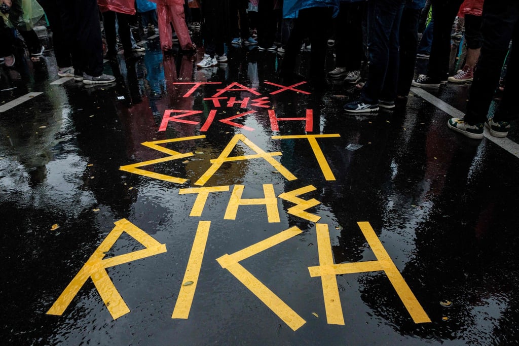 Students and activists create a sign on a read reading “Tax the rich, eat the rich” at a protest in Jakarta last month against President Prabowo Subianto’s budget-cutting policies. Photo: AFP