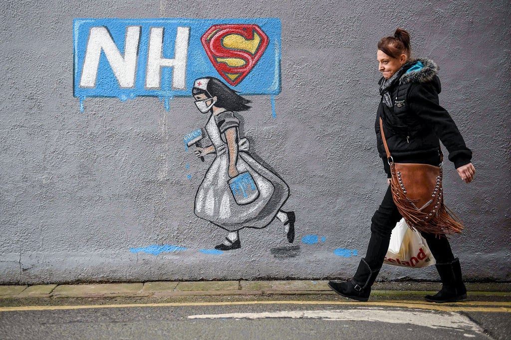 A pedestrian walks past graffiti depicting Britain’s National Health Service logo in northern England in 2020. Photo: AFP