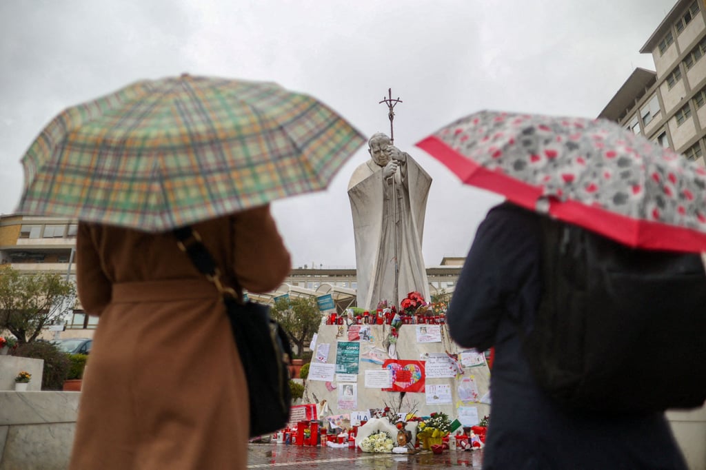 Women pray by the statue of late Pope John Paul II outside Gemelli Hospital in Rome, where Pope Francis is being treated. Photo: Reuters