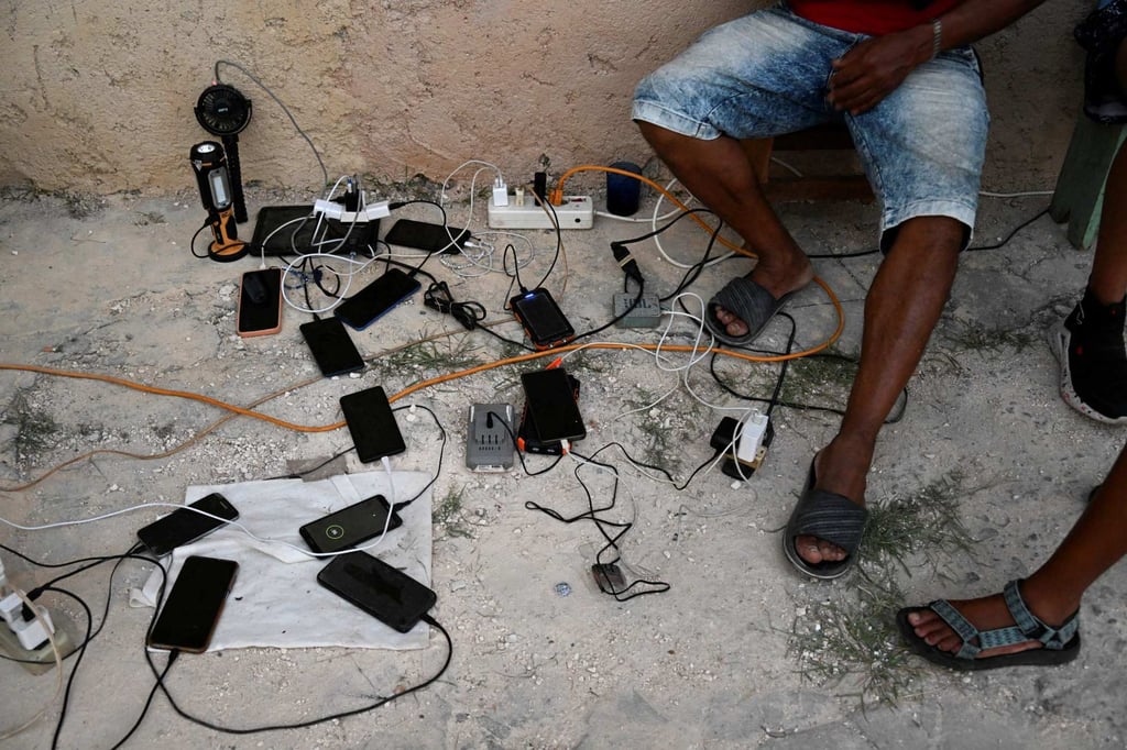 Cubans charge their mobile phones. Photo: AFP