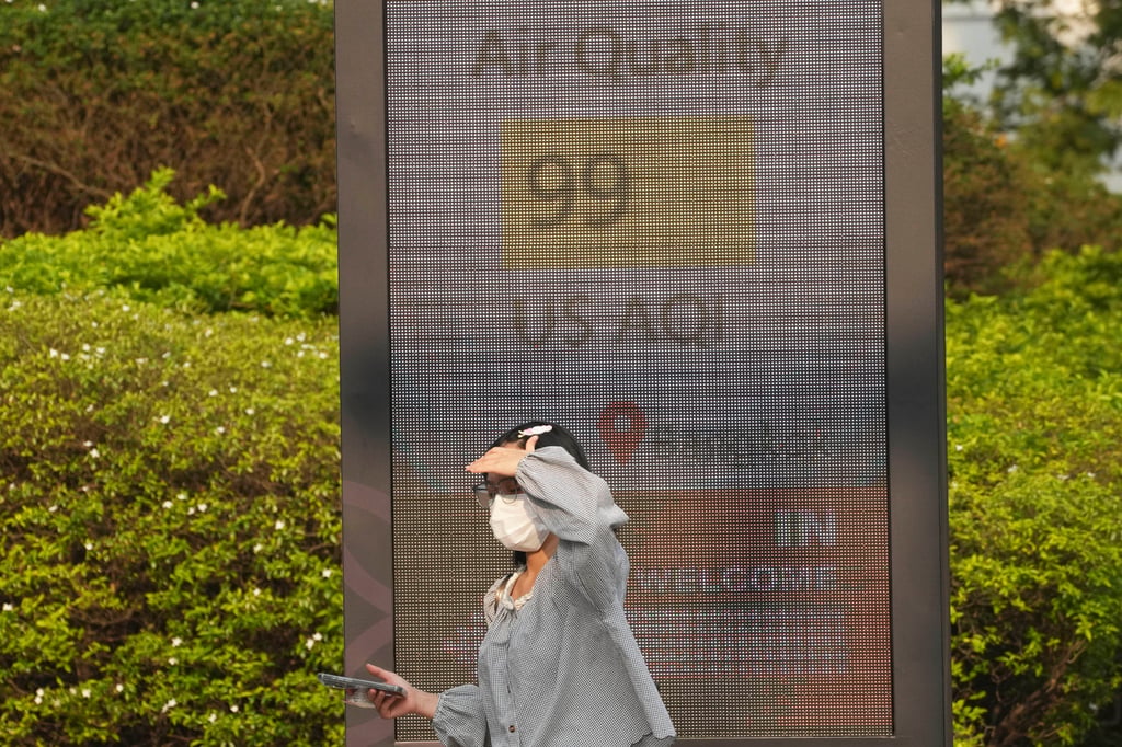 A pedestrian wears a face mask in front of a sign displaying an Air Quality Index in Bangkok, Thailand, on February 6. Photo: AP