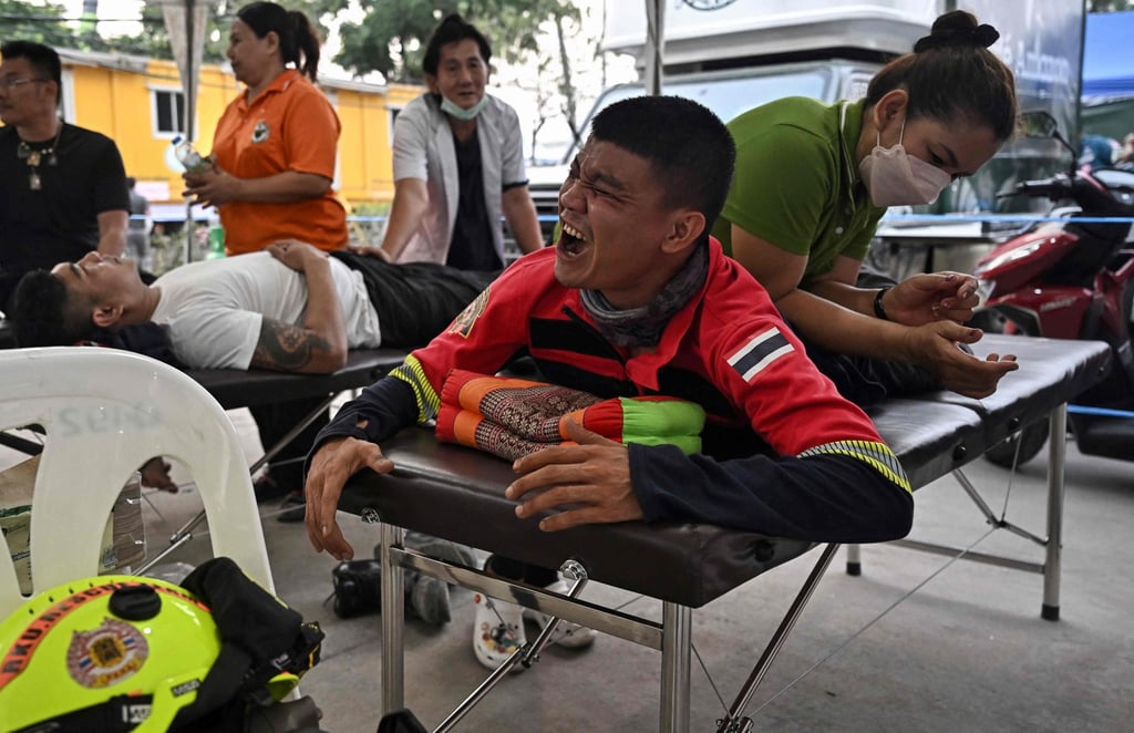 A rescuer is given a Thai massage at the site of an under-construction building collapse in Bangkok on Tuesday. Photo: AFP