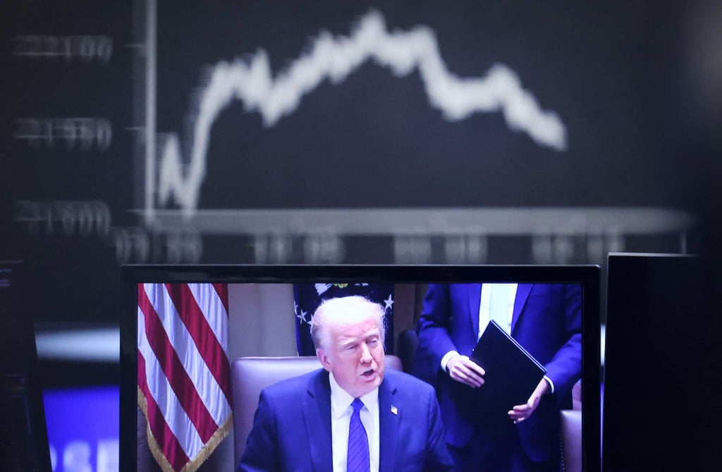 US President Donald Trump seen on a TV screen below a display showing the German Stock Market Index DAX at the stock exchange in Frankfurt on Thursday. Photo: afp