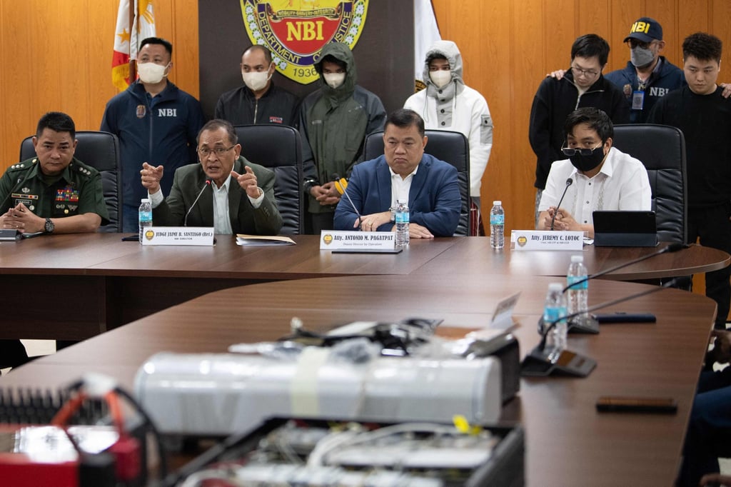 Chinese nationals (background third right and right) and their alleged Philippine accomplices (second left to fourth left), arrested for alleged espionage, presented behind (seated left to right) Armed Forces of the Philippines Public Affairs Office chief Colonel Xerxes Trinidad, National Bureau of Investigation (NBI) chief Jaime Santiago, NBI deputy chief for operations Antonio Pagatpat, and cybercrime unit chief Jeremy Lotoc during a press conference at the NBI office in Manila on February 25. Photo: AFP