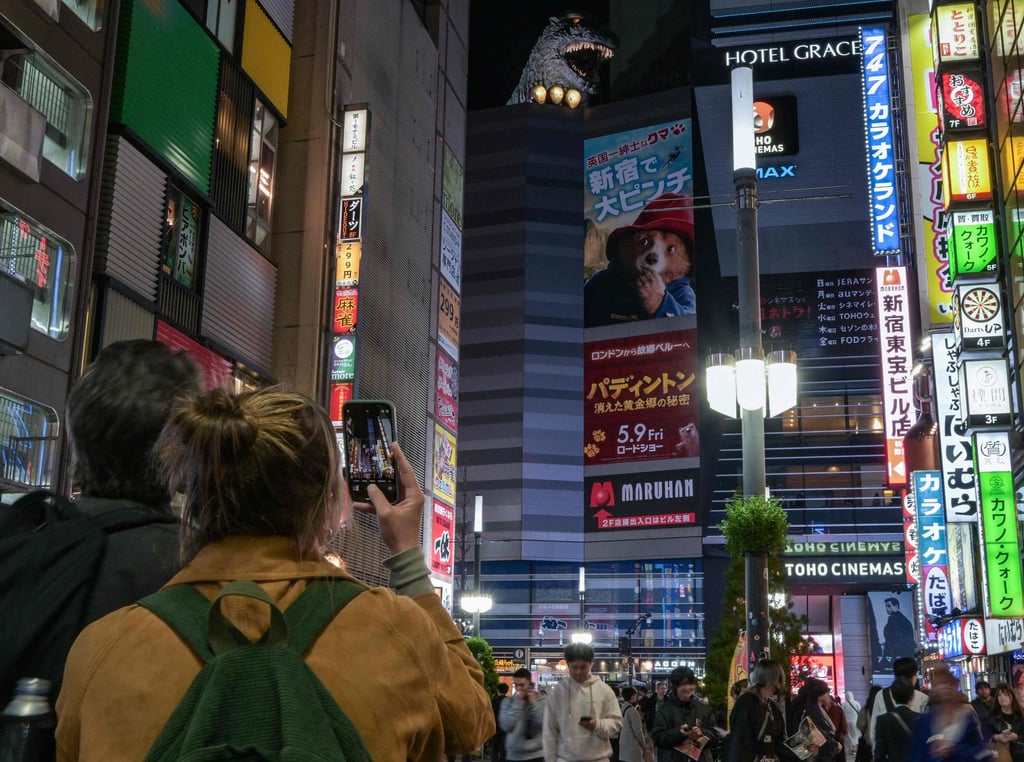 A tourist takes a photo of Godzilla at the top of a building in Kabukicho, Tokyo. Photo: AFP
