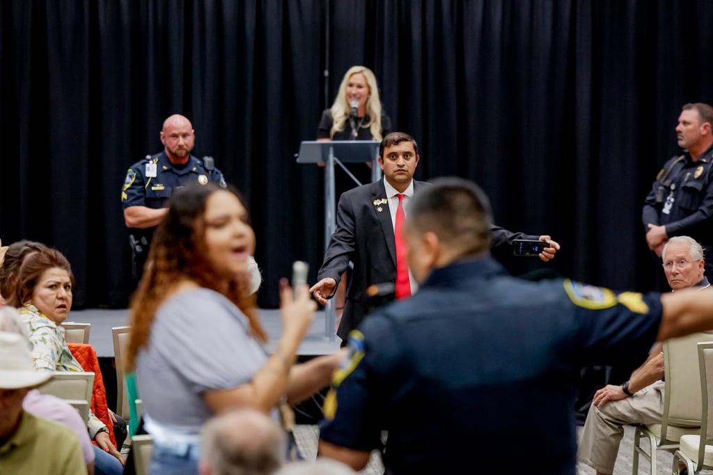 US Representative Marjorie Taylor Greene looks on as a protester is escorted out from a town hall meeting in Acworth, Georgia, on April 15. Photo: EPA-EFE