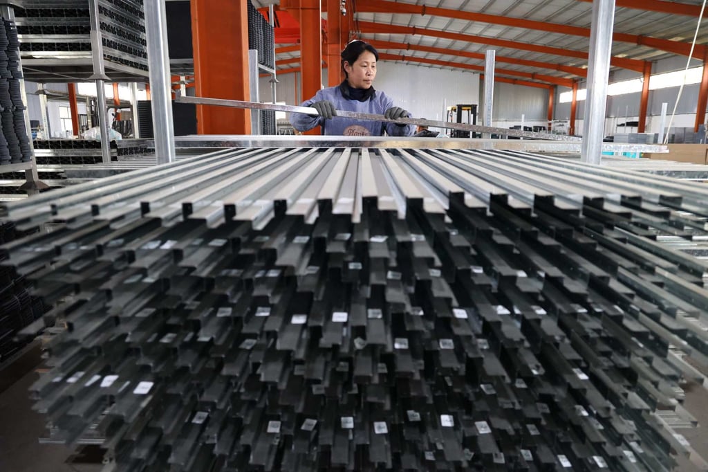 A worker stacks pressed steel items at a factory which produces metal products for export in China’s eastern Shandong province on April 15. Photo: AFP