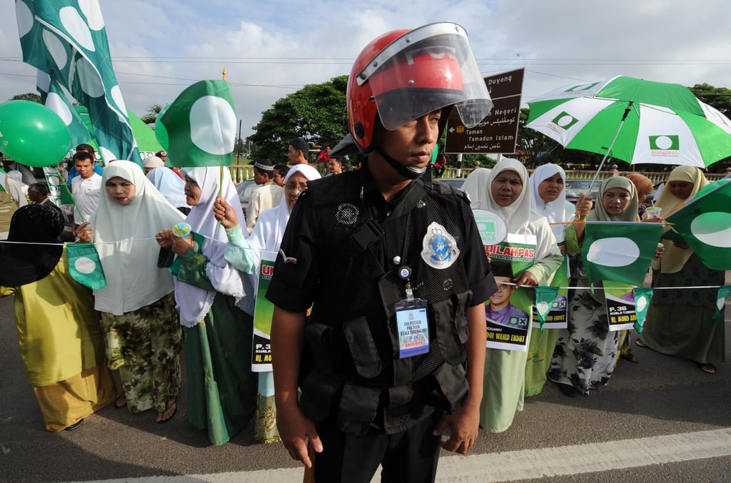 Security personnel watch over supporters of Parti Islam se-Malaysia (PAS) during a rally outside a polling station in Malaysia’s Terengganu state. Photo: AFP