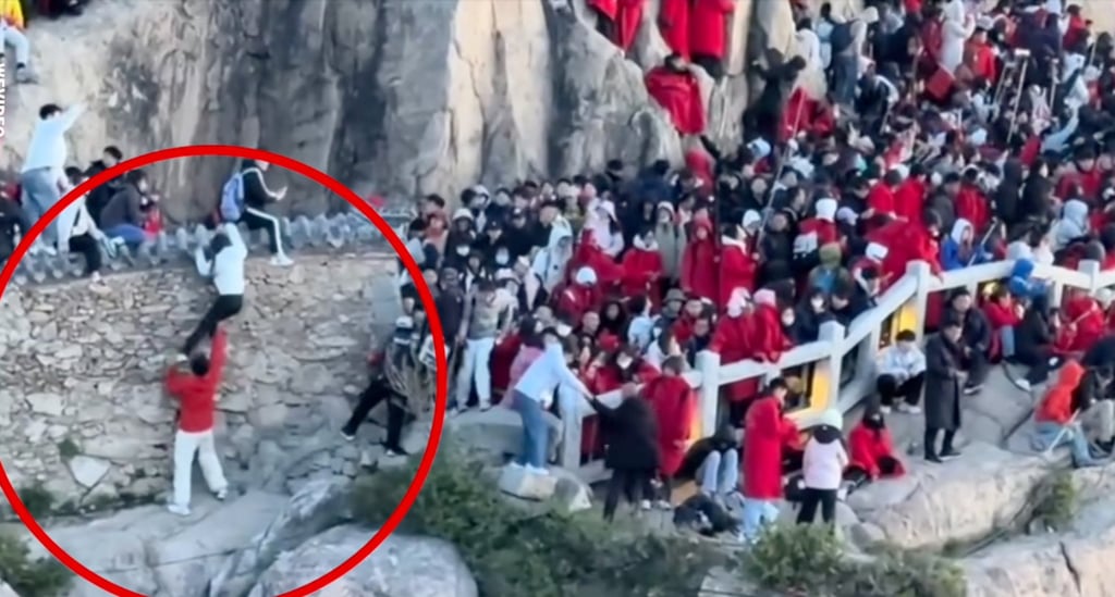 The couple, circled, climbed over a wall in an effort to beat big crowds on a mountain path. Photo: QQ.com