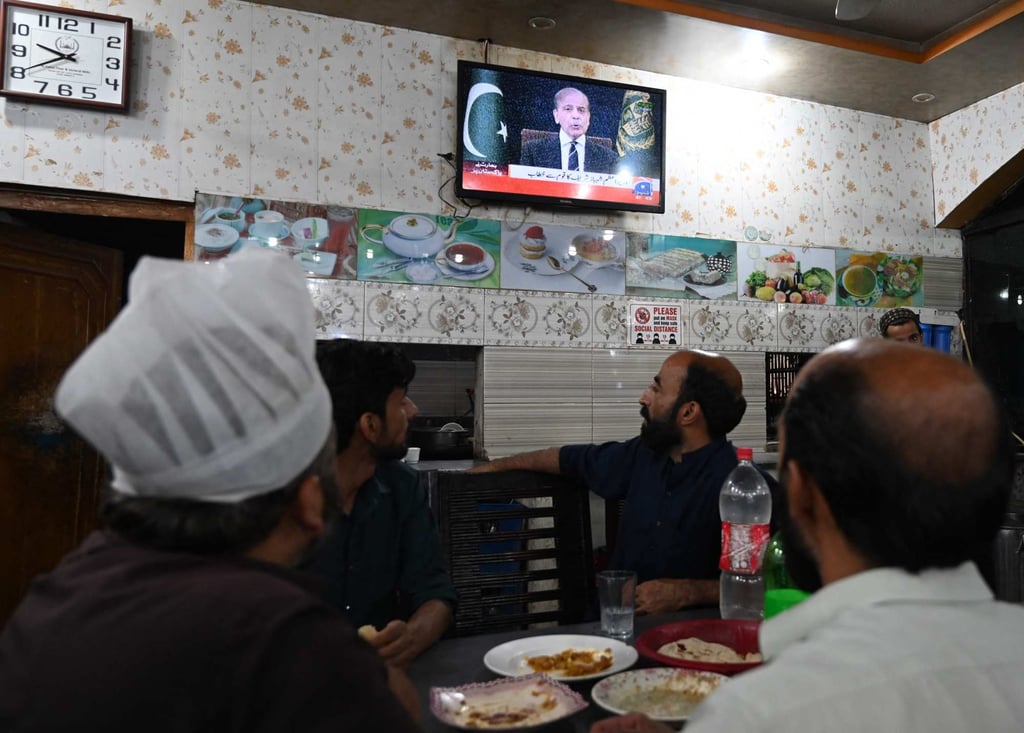 People watch television in a restaurant as Pakistan’s Prime Minister Shehbaz Sharif addresses the nation in Islamabad on Wednesday. Photo: AFP
