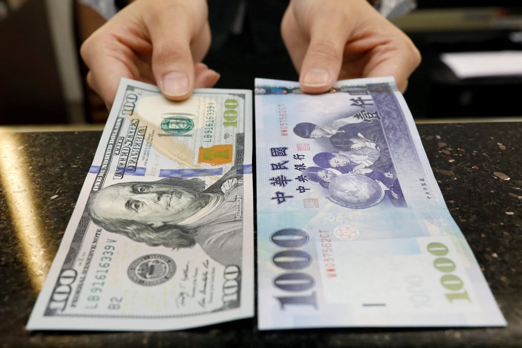 A teller poses with US$100 and NT$1,000 banknotes at a bank in Taipei, Taiwan. Photo: Reuters
