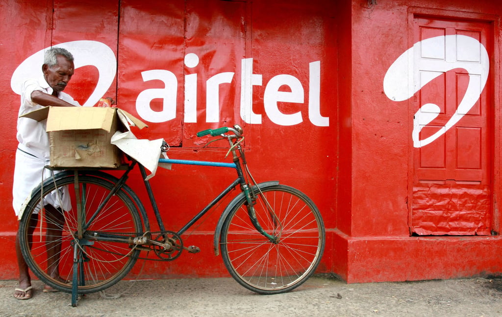 A man packs goods on the back of his bicycle next to an advertisement for Bharti Airtel in the southern Indian city of Kochi, in 2011. Photo: Reuters