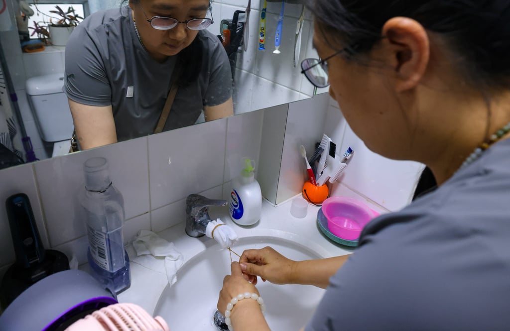 A resident wraps the water faucet with tissue to filter black particles. Photo: Nora Tam