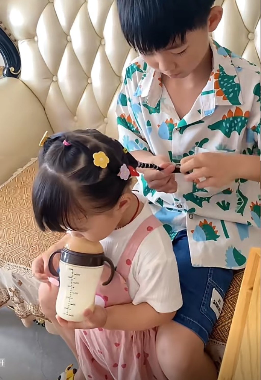 While her brother focuses on braiding, the little girl, often seen sipping milk from a bottle, appears to genuinely enjoy his attentive care. Photo: Douyin