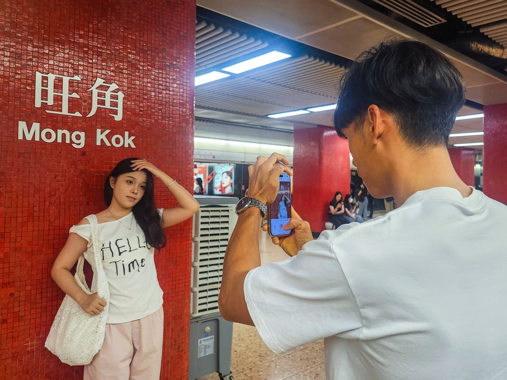 A mainland visitor poses next to the Mong Kok MTR station sign. The station and the Tsim Sha Tsui one are particularly popular with tourists from across the border. Photo: Timon Johnson