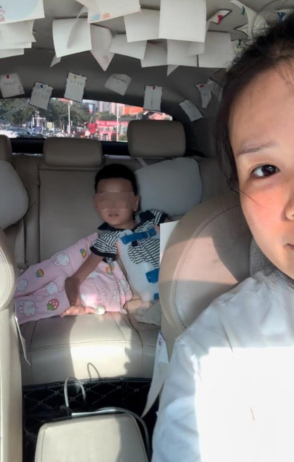 Little Momo relaxes in the back seat as his mother keeps watch over him in the rear-view mirror. Photo: Handout