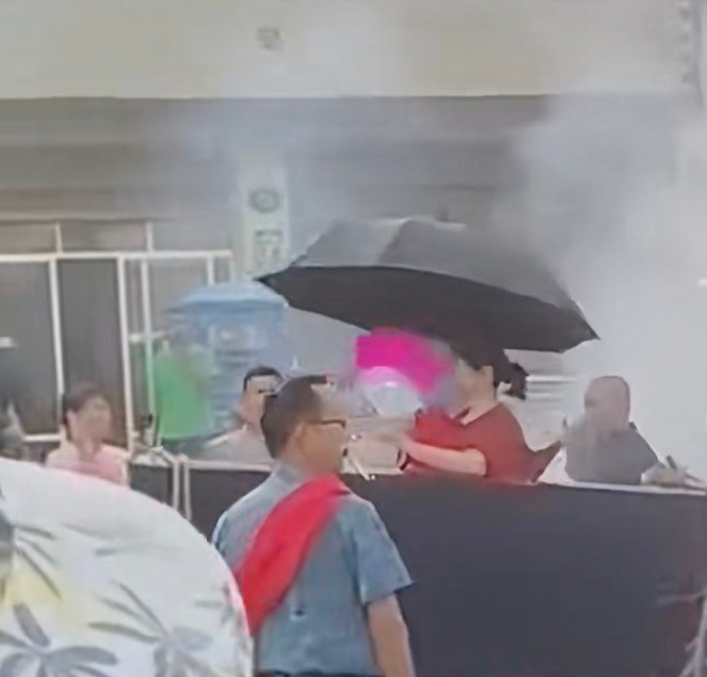 The woman, equipped with an umbrella and a fan, sits inside the coffin as the procession gets underway. Photo: Douyin