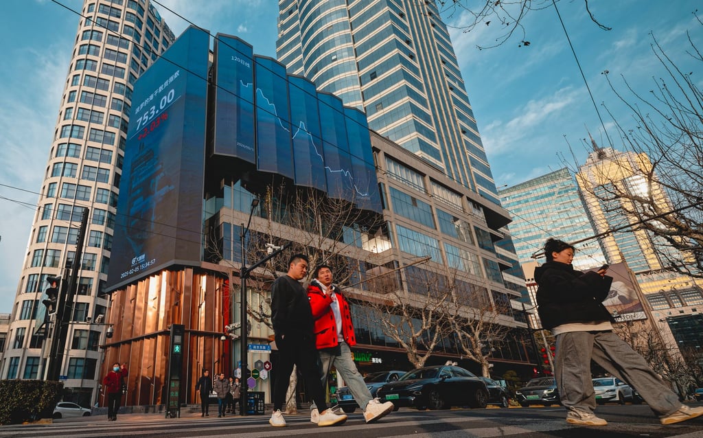 People cross a street near a screen showing stock exchange and economic data in Shanghai. Photo: EPA-EFE