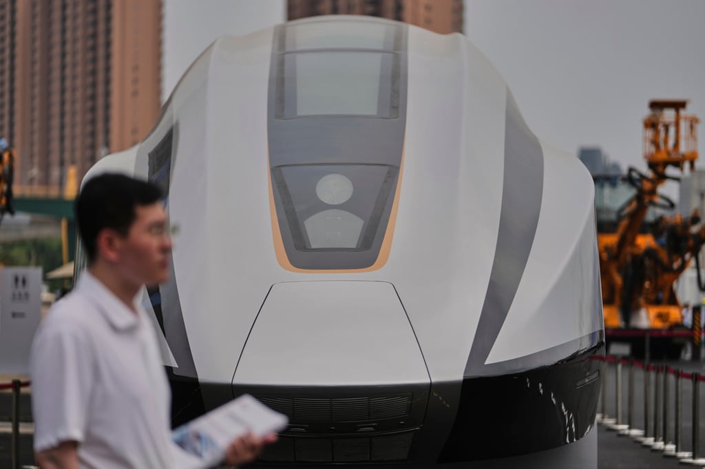 A volunteer holds leaflets as he stands near a 600km High Speed Maglev model showcasing at the National Railway Test Center during a tour by delegates to the World Congress on High-Speed Rail held in Beijing on July 9, 2025. Photo: AP