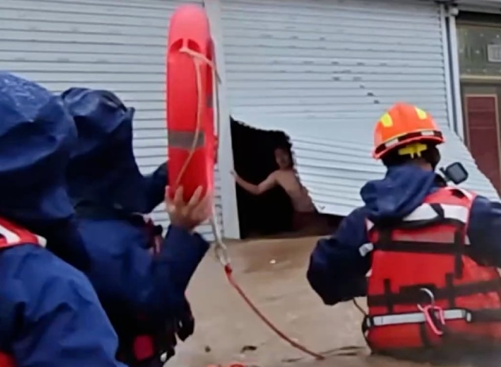 The husband can be seen looking out of his eatery as floodwaters rage around it and firefighters prepare to save him and his wife. Photo: Handout