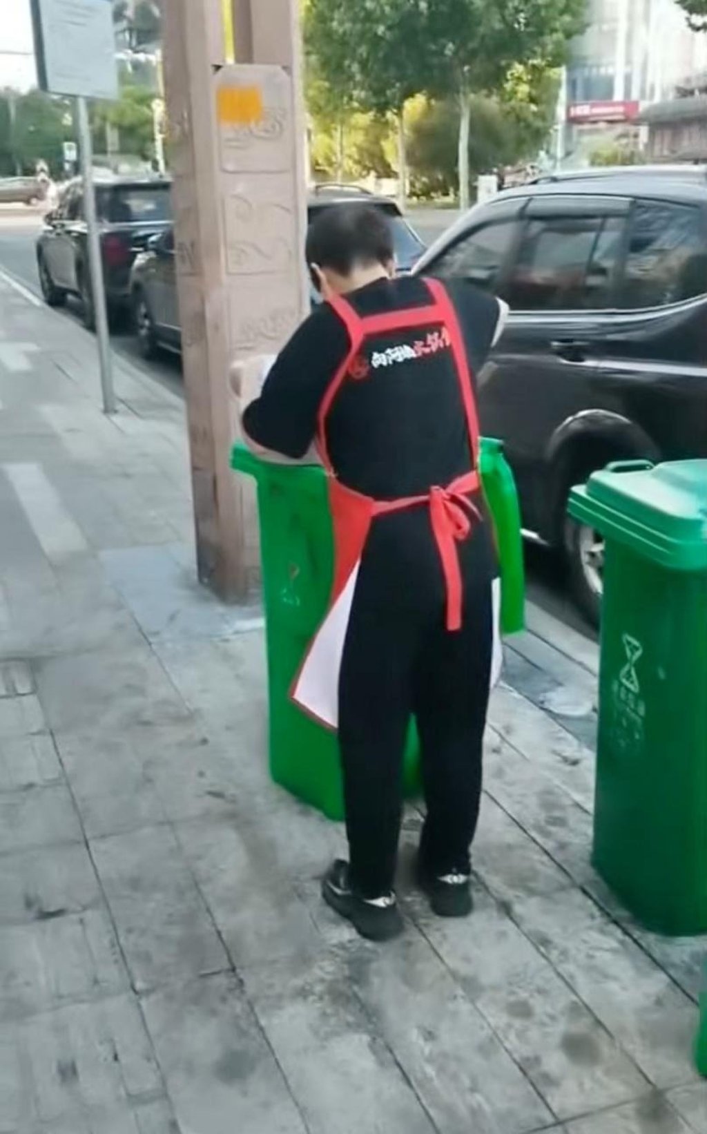 The woman worker was filmed scooping the oil into a bowl from a roadside bin. Photo: Handout