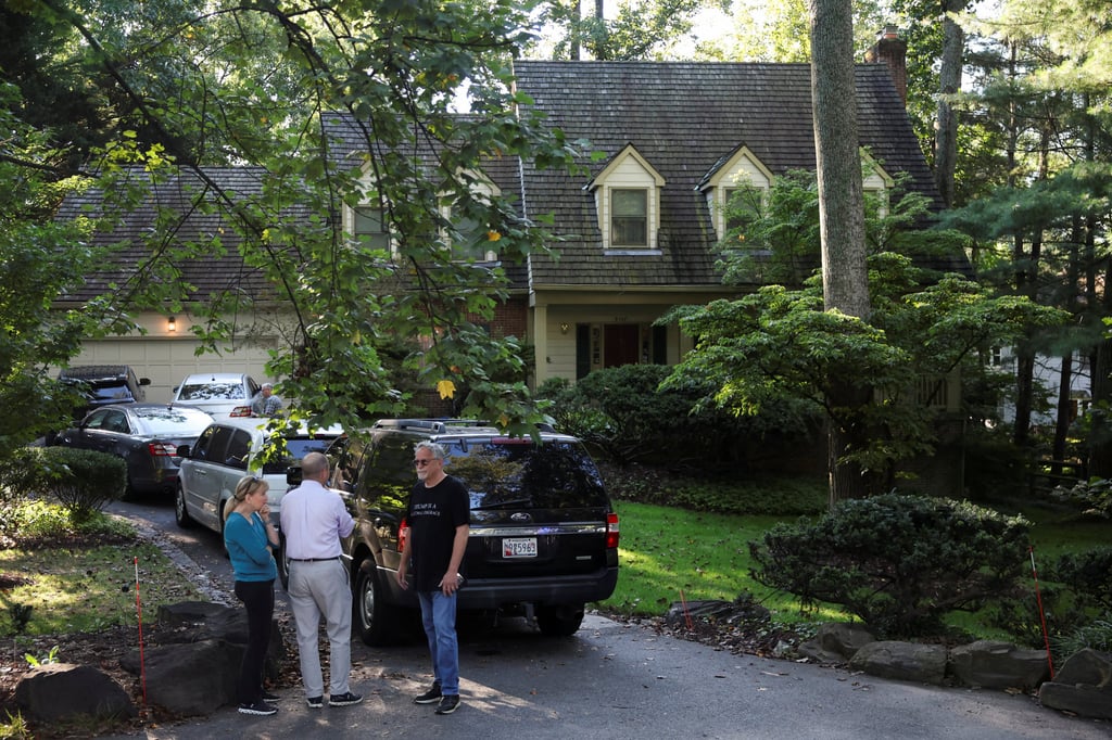 People stand outside the home of the former White House national security adviser John Bolton as it is searched by the US law enforcement agency in Bethesda, Maryland on Friday. Photo: Reuters