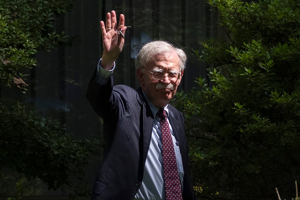 Former US national security adviser John Bolton waves as he arrives at his house in Bethesda, Maryland, on Friday. Photo: AP