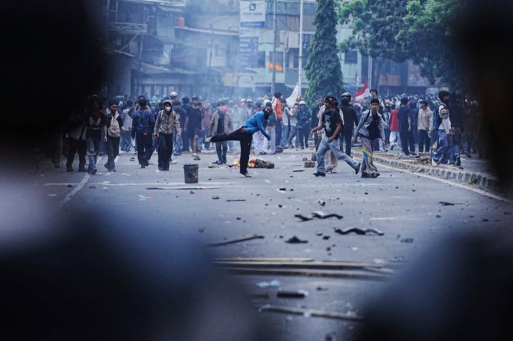 Protesters throw rocks in Jakarta on Monday while calling for a salary cut for parliamentarians. Photo: AP