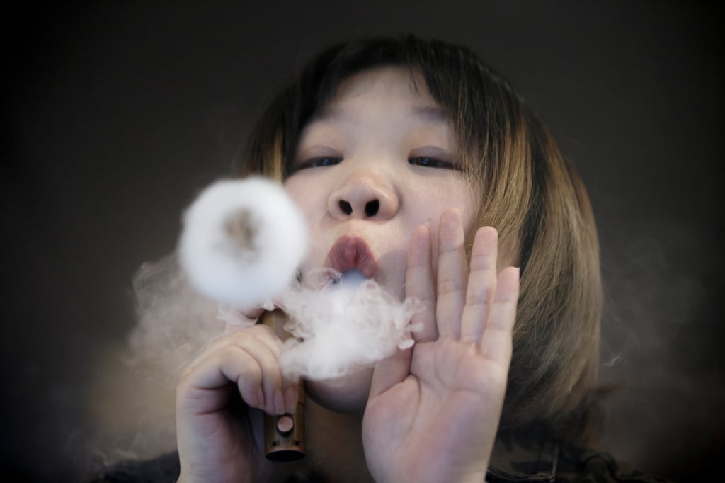 A saleswoman in Beijing, China uses a vaping product. Singapore banned the purchase, possession and use of vapes in 2018, and will toughen those laws from next month. Photo: Reuters