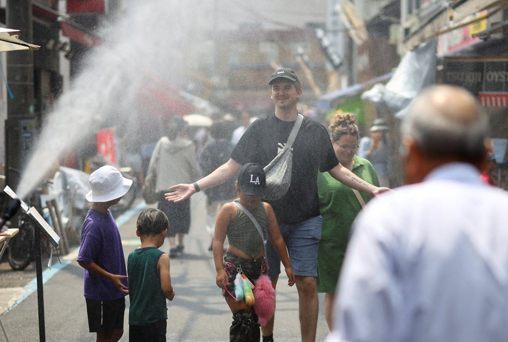 Foreign tourists walk through a cooling mist amid a heatwave in Tokyo late last month. Photo: Reuters