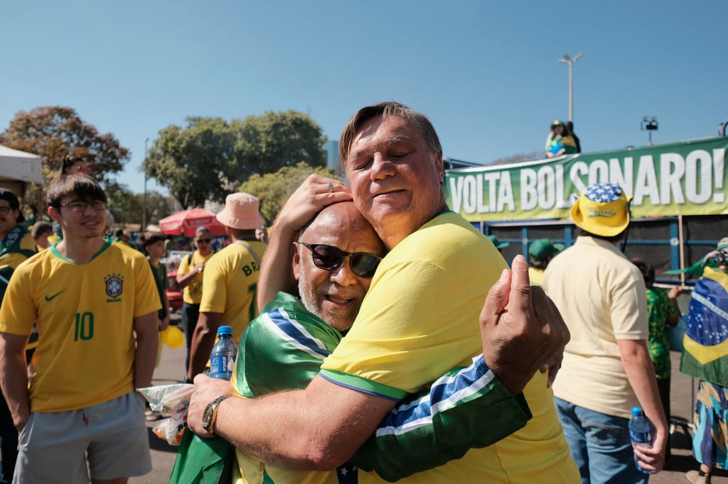Uber driver Alessandro Almeida, a Bolsonaro supporter known for his resemblance to the Brazilian ex-president, embraces another man during a protest in Brasilia on Sunday. Photo: Reuters