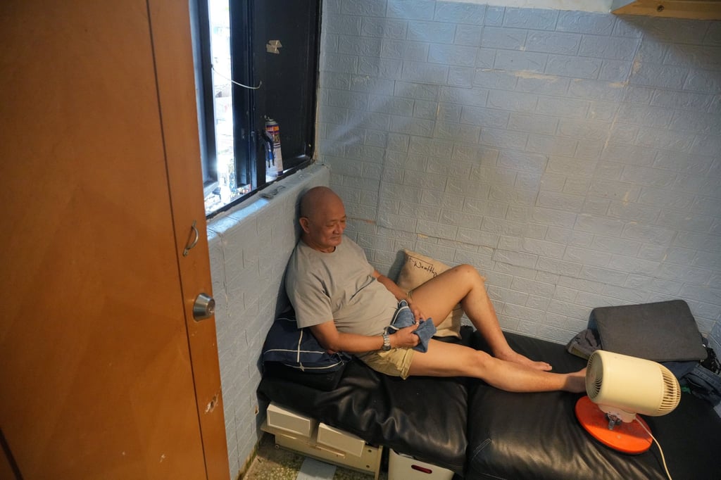 Samuel Wong uses a fan to cool himself down while resting in his subdivided flat. Photo: May Tse