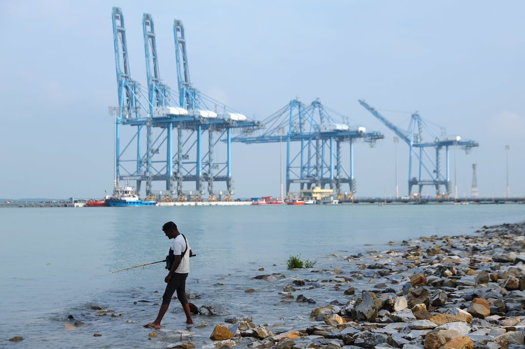 A man fishes with cranes seen in the background at Port Klang, outside Kuala Lumpur on September 10. Malaysia is among Asean members slapped with a 19 per cent US tariff. Photo: EPA