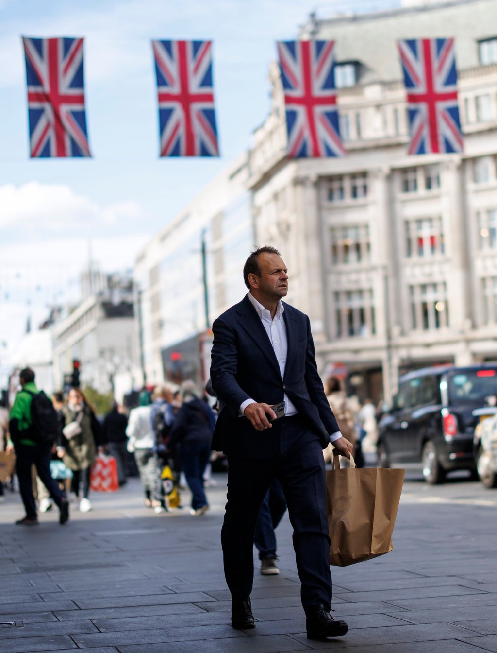 A man strolls down Oxford Street with a shopping bag in London. Photo: EPA
