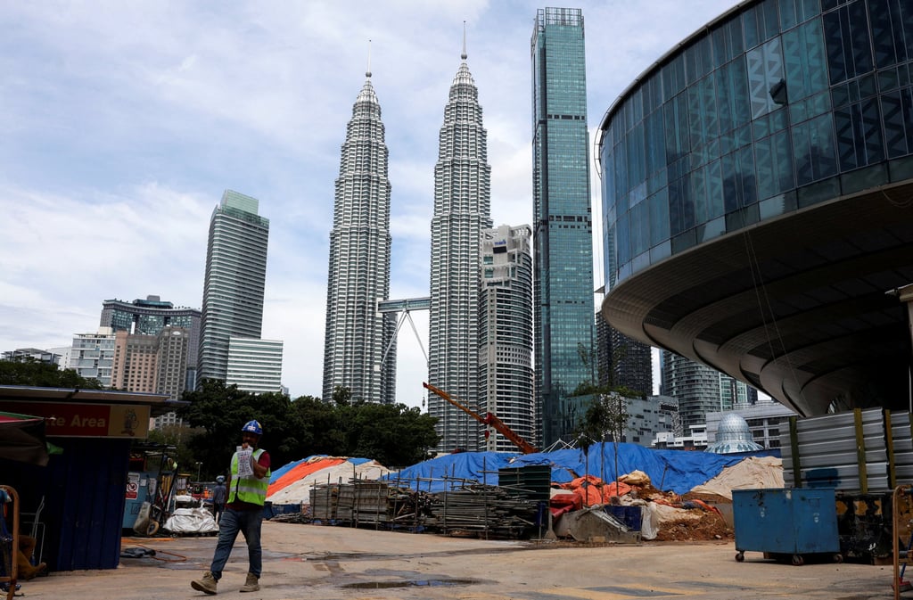 A worker walks out of a construction site, next to the Petronas Twin Towers, on Friday. Malaysia plans to spend 470 billion ringgit to boost infrastructure, expand rural digital access and help youth boost their income. Photo: Reuters