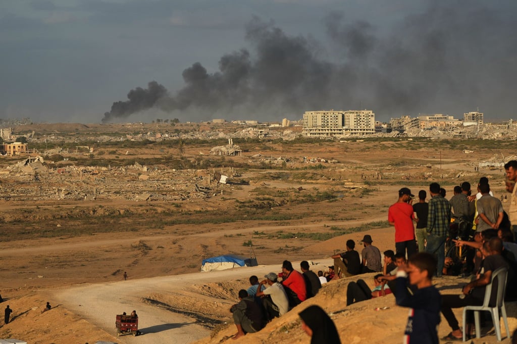 Displaced Palestinians watch smoke rise after Israeli military strikes in Gaza on Thursday. Photo: AP